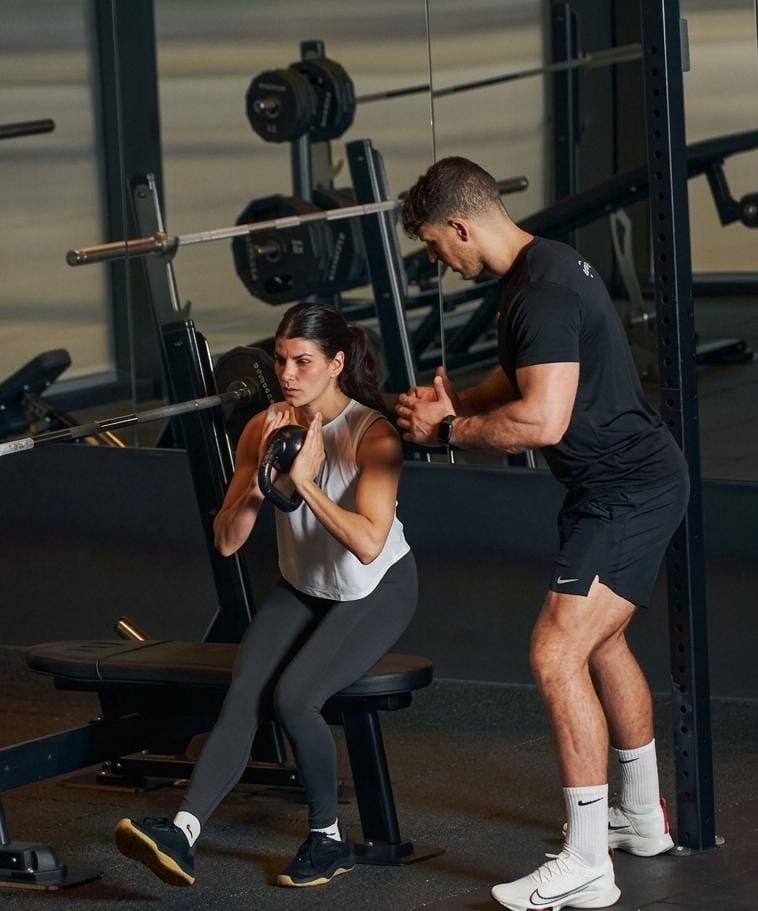 A TrueCore coach guiding a client through a goblet squat
